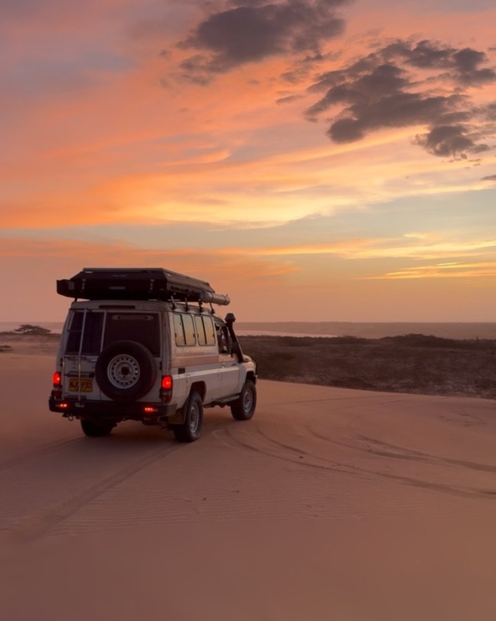 Land Cruiser con carpa de techo en la playa al atardecer